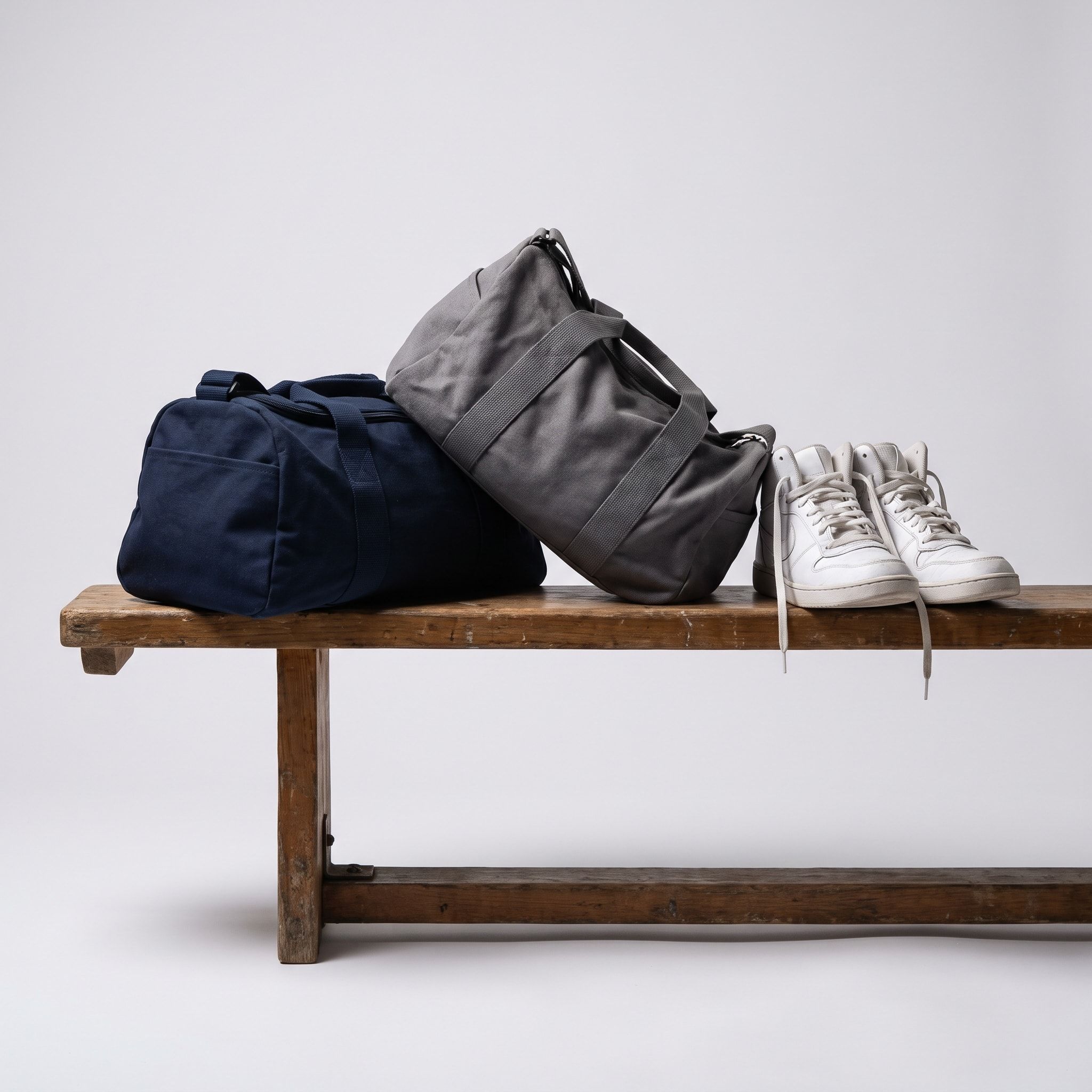 Two kit bags and basketball shoes on a bench